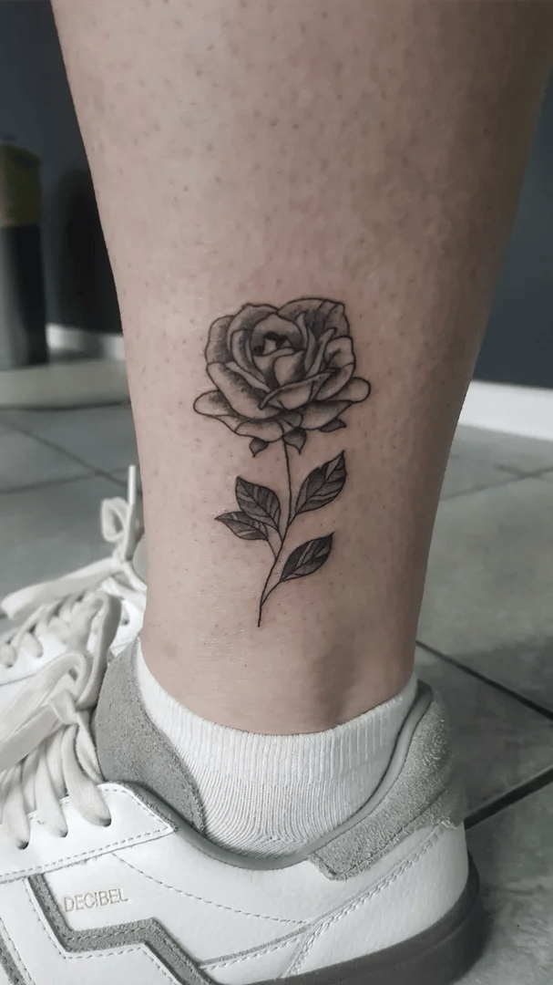 Delikatne tatuaże damskie: róża fine line na łydce