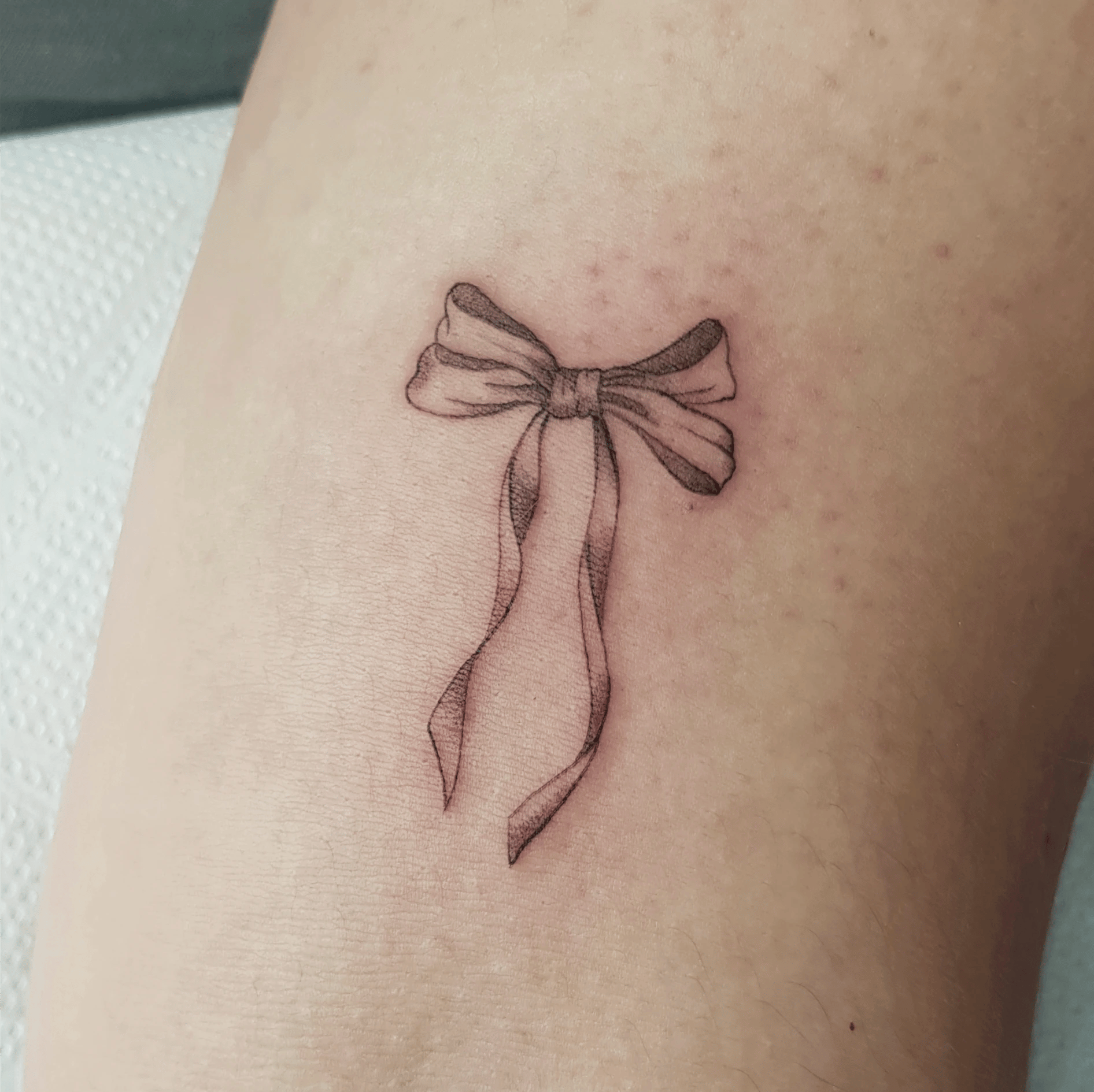 Delikatne tatuaże damskie: kokarda na przedramieniu